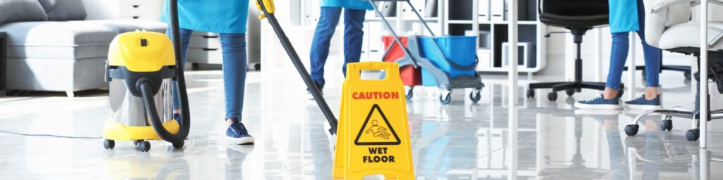 Commercial cleaner working beside a wet-floor safety sign