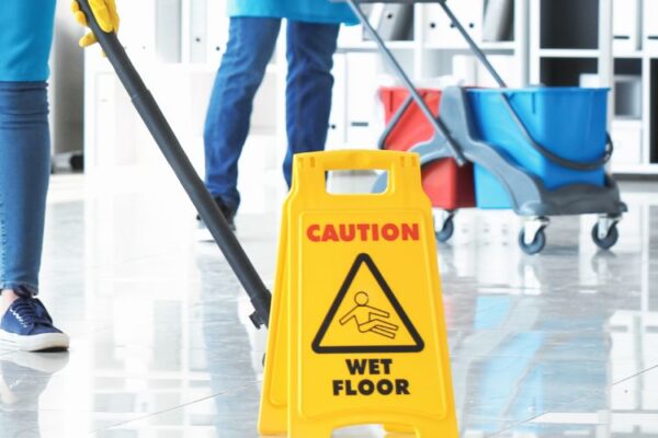 Commercial cleaner working beside a wet-floor safety sign
